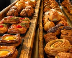 Rows of fresh croissants, danishes and swirls on a wooden counter
